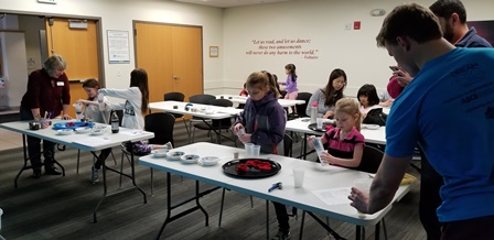 Librarian Judi Koch, left, and ASCE student volunteer Kendall help children and their parents assemble filters.